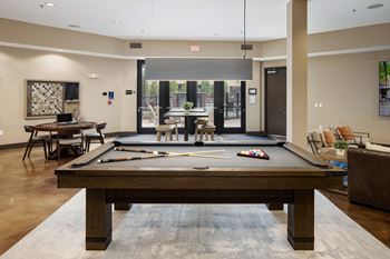 A pool table is in the middle of a room with a couch and chairs.